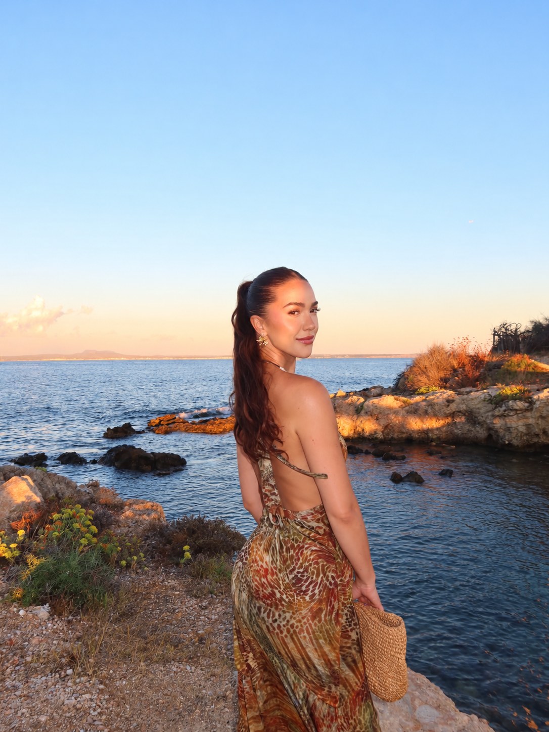 Ashley Boston looking back over a rocky sunset coast